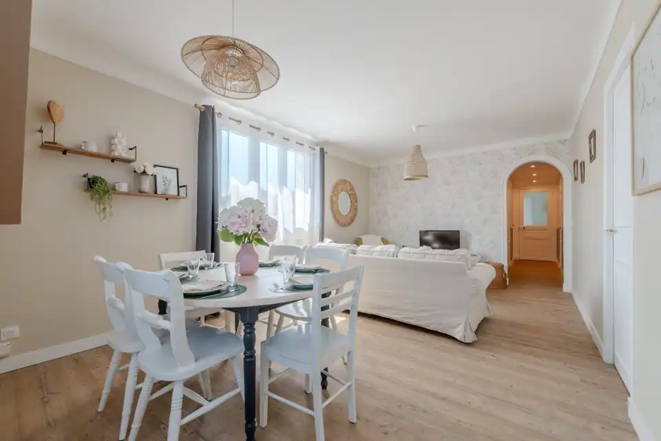Séjour lumineux d'un logement préparé, table dressée et canapé blanc