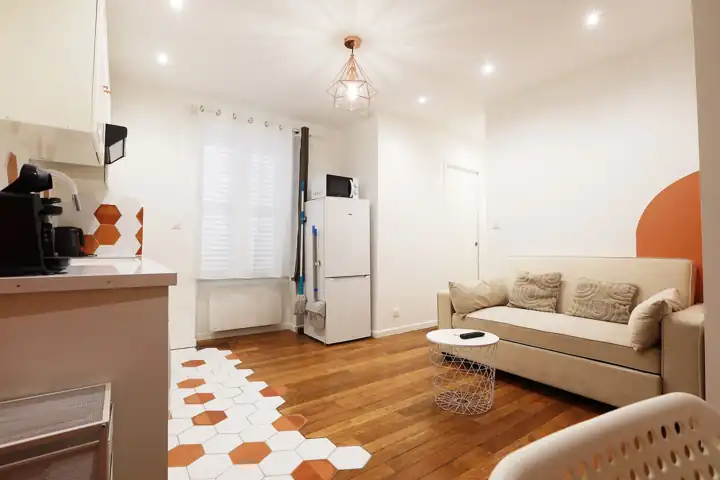 Studio lumineux avec canapé beige et carrelage hexagonal